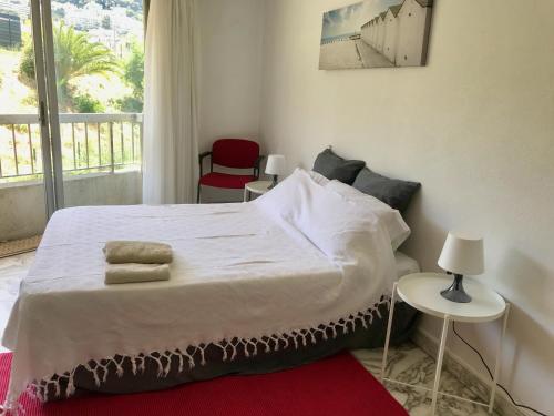 une chambre avec un lit avec deux chaises et une fenêtre dans l'établissement La résidence du port, à Nice