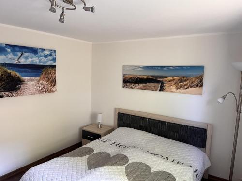 a bedroom with a bed and two pictures on the wall at Fewo Eckernförde mit Meerblick in Eckernförde