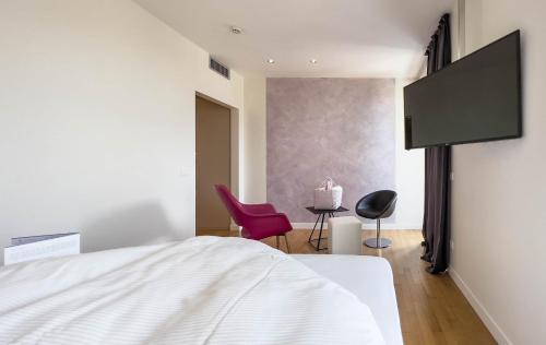 a bedroom with a white bed and a pink chair at Tobago in Garda