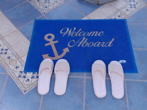 a welcome board with a pair of shoes on the floor at Yacht Marine Maison in Naxos Chora