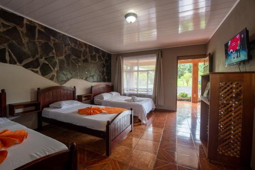 Hotel & Hot Springs Sueño Dorado في فورتونا: غرفة نوم بسريرين وجدار حجري