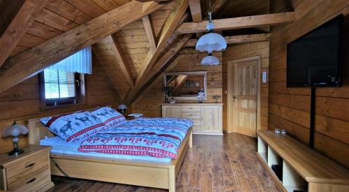 a bedroom in a log cabin with a bed and a flat screen tv at Roubenka Lomná in Horní Lomná