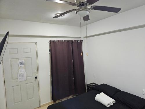 a bedroom with a ceiling fan and a bed and a door at El Padrino in Akumal
