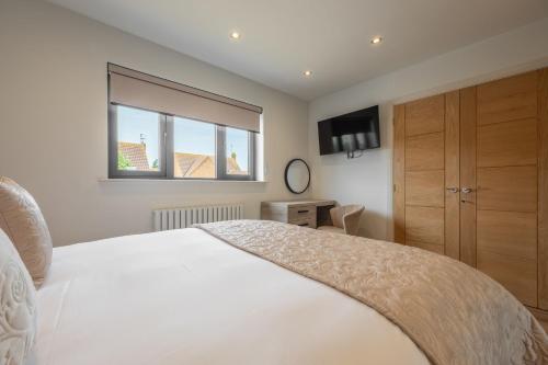 ein Schlafzimmer mit einem großen weißen Bett und einem Fenster in der Unterkunft Seaspray in Hunstanton