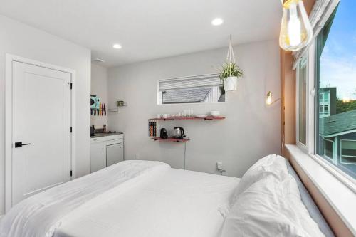 a white bedroom with a bed and a window at Pingu's sweet suite - Micro Studio - 91Walkscore in Seattle