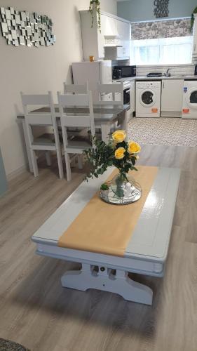 a kitchen with a table with yellow flowers on it at Lower Main Street Apartment in Letterkenny