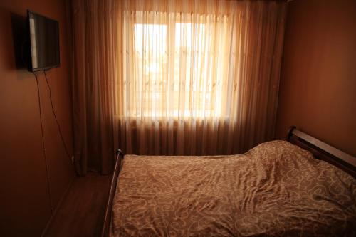 um quarto com uma cama e uma janela com cortinas em 10 мин ходьбы от фонтана. Делаем отчетные документы. em Vinnytsya