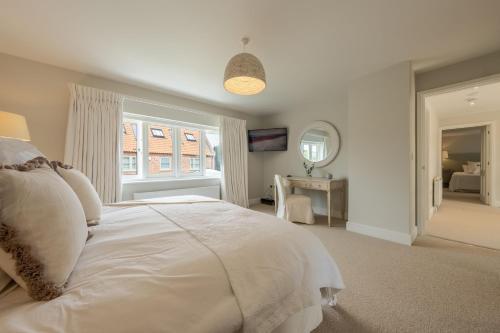 a white bedroom with a bed and a mirror at Limestone House in Burnham Market
