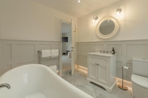a bathroom with a sink and a toilet and a mirror at Limestone House in Burnham Market