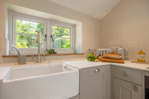 a white kitchen with a sink and a window at Willow Cottage SC in South Creake