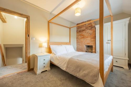 a bedroom with a bed and a brick wall at Willow Cottage SC in South Creake