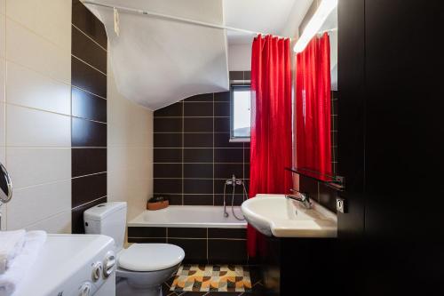 a bathroom with a white toilet and a red shower curtain at Anna Maria in Kalamitsi Amygdali