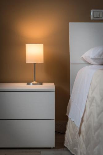 a white dresser with a lamp on it next to a bed at Relax Ciampino - By Good Time Apartments in Ciampino