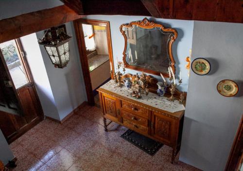 an old wooden dresser with a mirror on a wall at Casa Rural La Aldea in Pola de Laviana