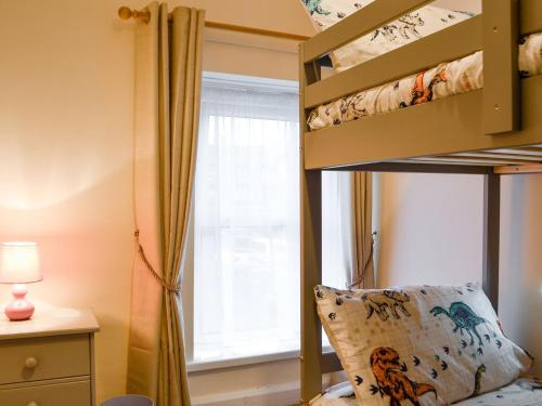 sypialnia z łóżkiem piętrowym i oknem w obiekcie Rhonas Cottage w mieście Abergavenny