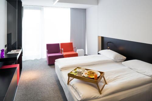 a hotel room with a bed, chair, table and a television at Hotel Privo in Târgu-Mureş