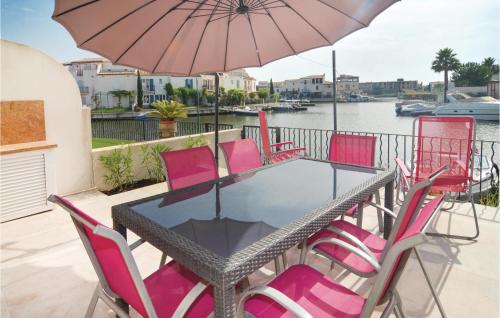 - une table avec des chaises roses et un parasol sur le balcon dans l'établissement 3 Bedroom Nice Home In Aigues-Mortes, à Aigues-Mortes