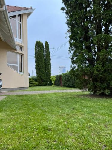 a yard of a house with green grass and trees at Mol-Ker-Vill Apartment in Lenti