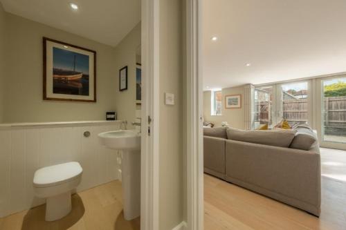 a bathroom with a toilet a sink and a couch at 1 Railway Cottages H in Holt