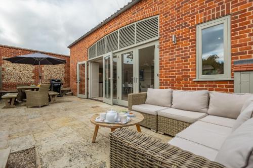 a patio with a couch and a table at 1 Railway Cottages H in Holt