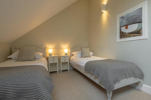 two twin beds in a room with two lamps at 1 Railway Cottages H in Holt