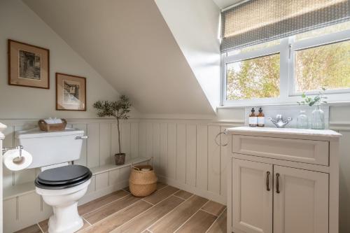 a bathroom with a toilet and a sink and a window at Evergreen in Thornage