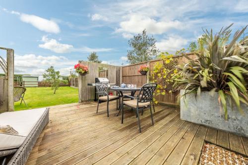 a patio with a table and chairs on a wooden deck at Cartshed Lodge in Hoveton