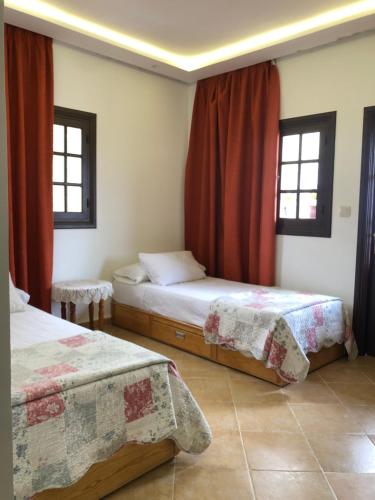 a bedroom with two beds and two windows at Mina House in Chefchaouen