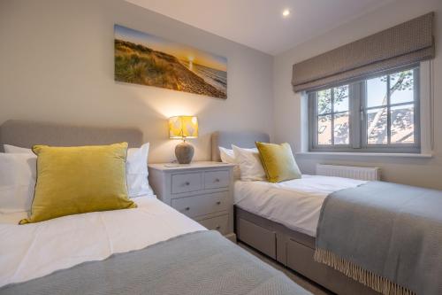 a bedroom with two beds and a window at Bluebell Cottage in Thornham