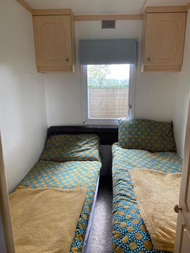 two beds in a small room with a window at Monks Heath fold mobile home in Macclesfield