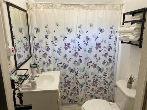 a bathroom with a shower curtain with a toilet and a sink at Weekendz- Cozy 2BRD Suite in Port Antonio