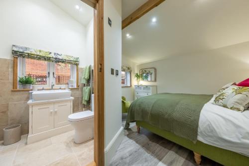 ein Schlafzimmer mit einem Bett und ein Badezimmer mit einem Waschbecken in der Unterkunft The Gardeners Cottage E 