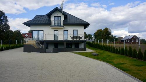 une grande maison blanche avec un toit noir dans l'établissement Agroturystyka Ostrowie, à Dąbrowa Grodzieńska-Wieś