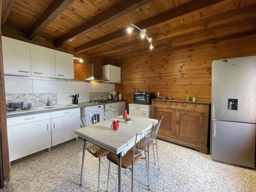 une cuisine avec une table et un réfrigérateur dans l'établissement Gîte romantique en pleine nature avec étang privatif et cheminée - FR-1-489-447, à Châtel-Montagne