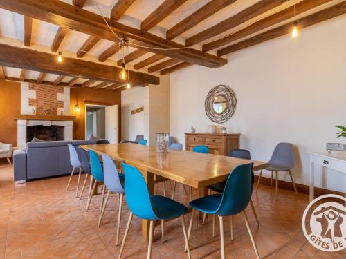 une grande salle à manger avec une table en bois et des chaises bleues dans l'établissement Gîte de groupe avec salle de jeux, jardin 4000m², proche forêt de Chandelais et Zoo de la Flèche - FR-1-622-56, à Baugé