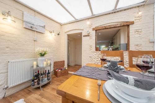 ein Esszimmer mit einem Tisch und Weingläsern in der Unterkunft Daisy Cottage H in Holt