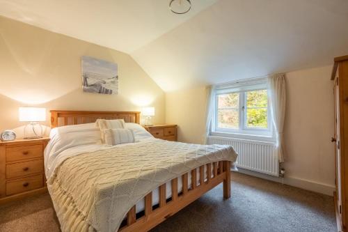 ein Schlafzimmer mit großem Bett und Fenster in der Unterkunft Daisy Cottage H in Holt