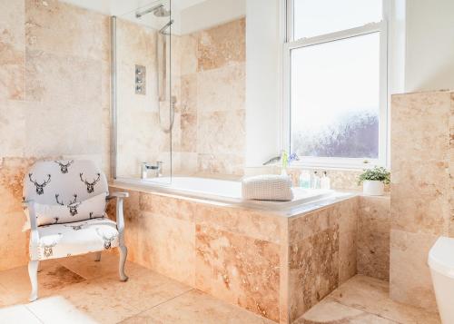 a bathroom with a tub and a chair and a window at Strathallan Bed and Breakfast in Grantown on Spey