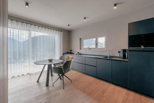 a kitchen with a table and a sink and a tv at LA LIBELLA - slow living Suites in Merano
