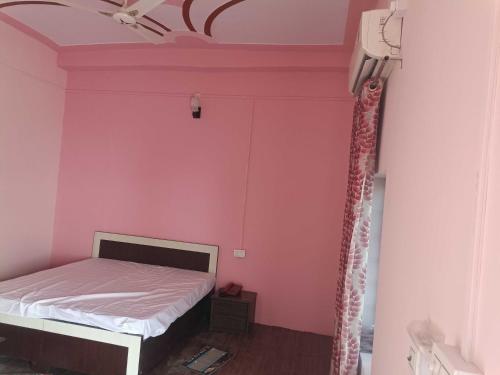 a bedroom with a pink wall and a bed at POP 80511J Palki Hotel And Marriage Palace in Singhāna