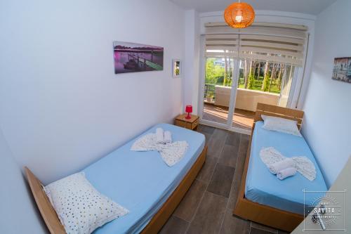a bedroom with two beds and a window with a view at Gjiri i Lalzit - Savita Apartments - Kompleksi Turistik Lura 2 in Mullini i Danit