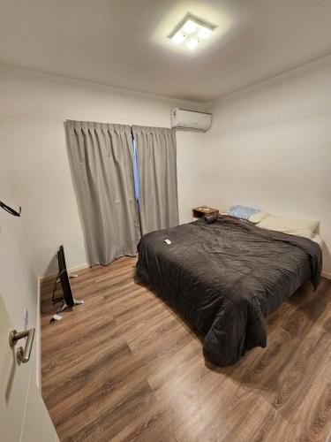 a bedroom with a bed and a wooden floor at Departamento amoblado con balcón y cochera en la entrada de escobar in Belén de Escobar