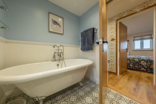 a bathroom with a bath tub and a bedroom at Bumblebee Cottage 