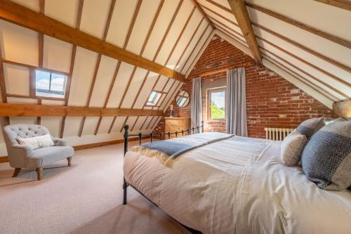 a bedroom with a bed and a chair in a attic at The Cart Shed NC in North Creake