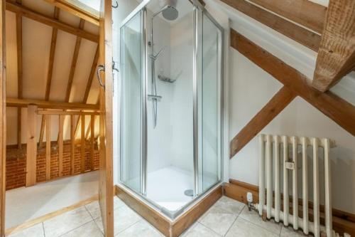 a glass shower in a room with a wooden ceiling at The Cart Shed NC in North Creake