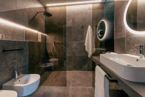 La salle de bains est pourvue d'un lavabo, de toilettes et d'un miroir. dans l'établissement LA LIBELLA - slow living Suites, à Merano