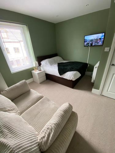 a bedroom with a bed and a couch and a tv at Modern En-Suite Rooms Town Centre Self-Check In in Barnsley