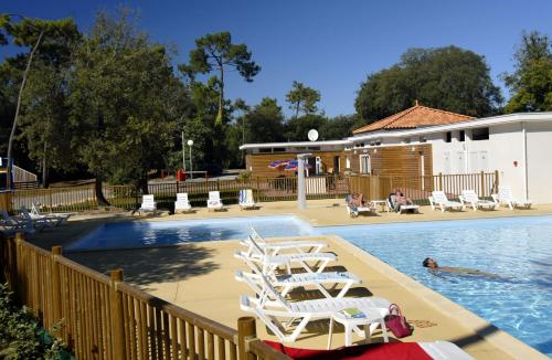 a swimming pool with lounge chairs next to a swimming pool at Domaine Résidentiel de Plein Air Odalys Monplaisir in Saint-Trojan-les-Bains