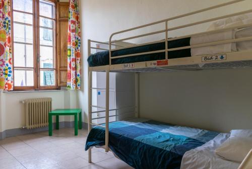a bedroom with two bunk beds and a green table at Hostel Pisa Tower in Pisa