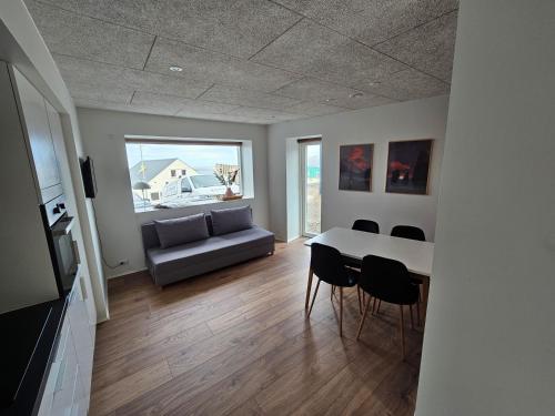 a living room with a table and chairs and a couch at Brand new apartment with stunning skyline views in Tórshavn